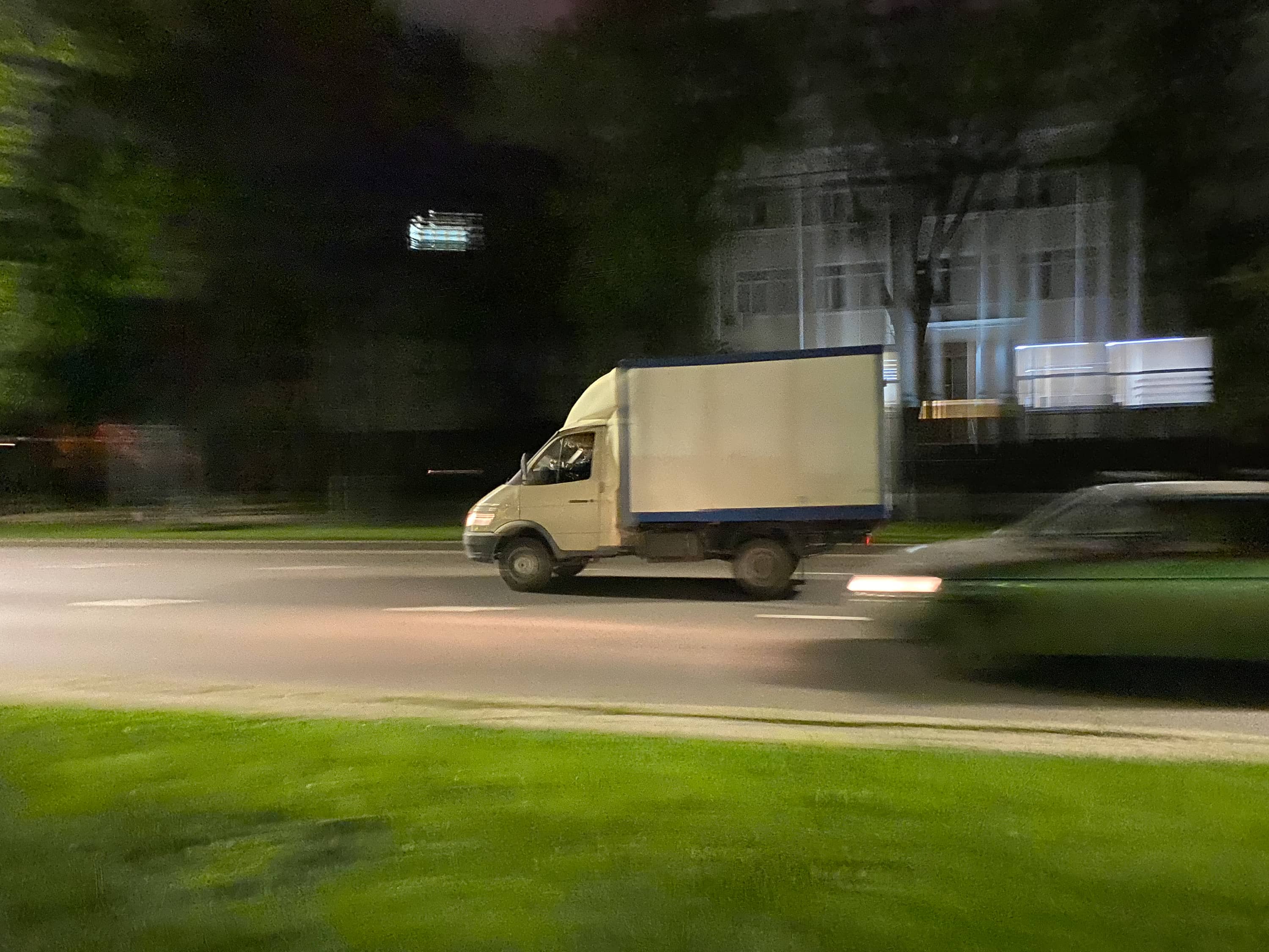 Белая газель едет по улице. Фургон чёткий, фон смазан, создан эффект движения