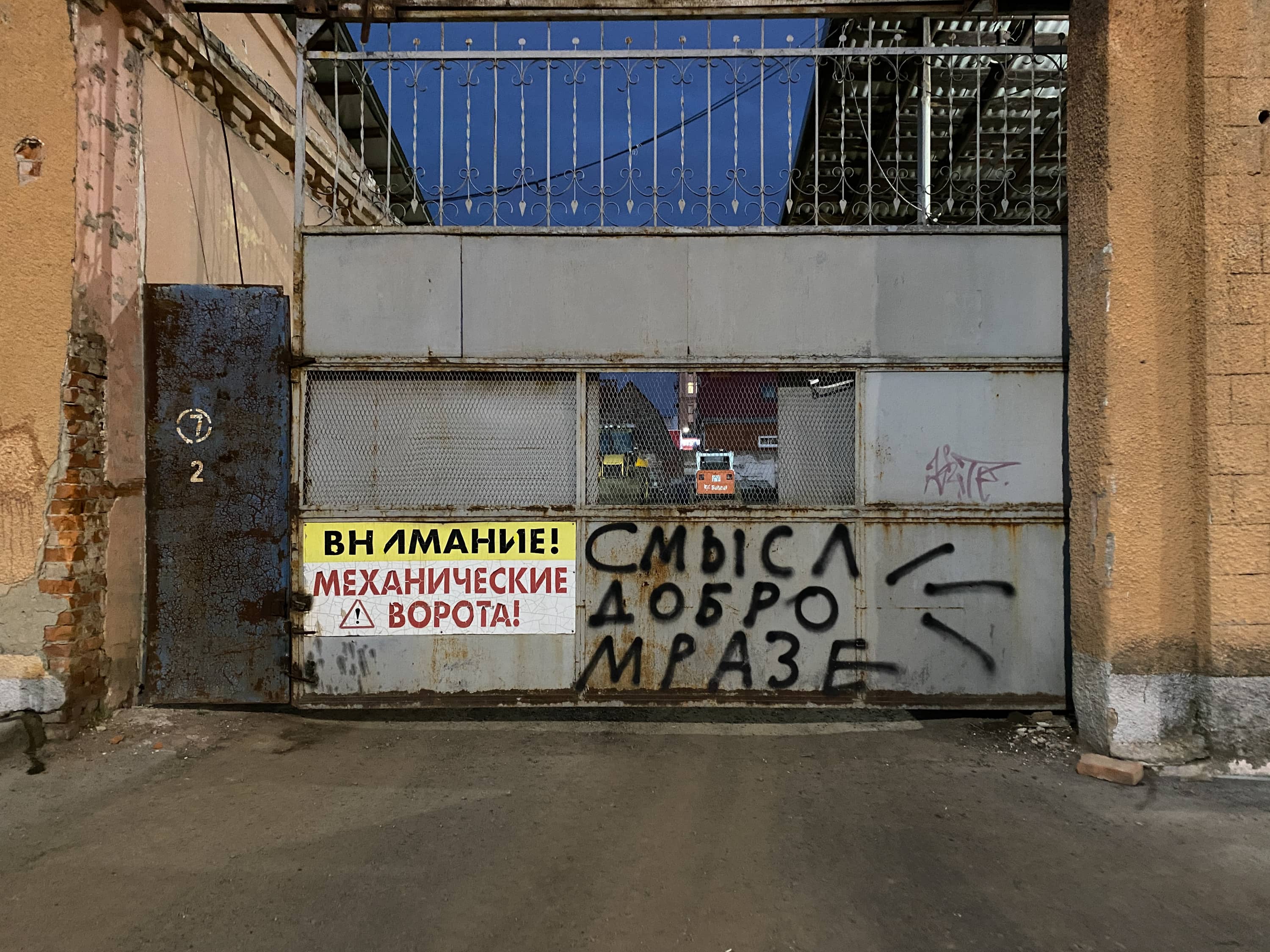 Ворота на стройку, на воротах надпись «Внимание! Механические ворота» и граффити «Смысл, добро, мразе»